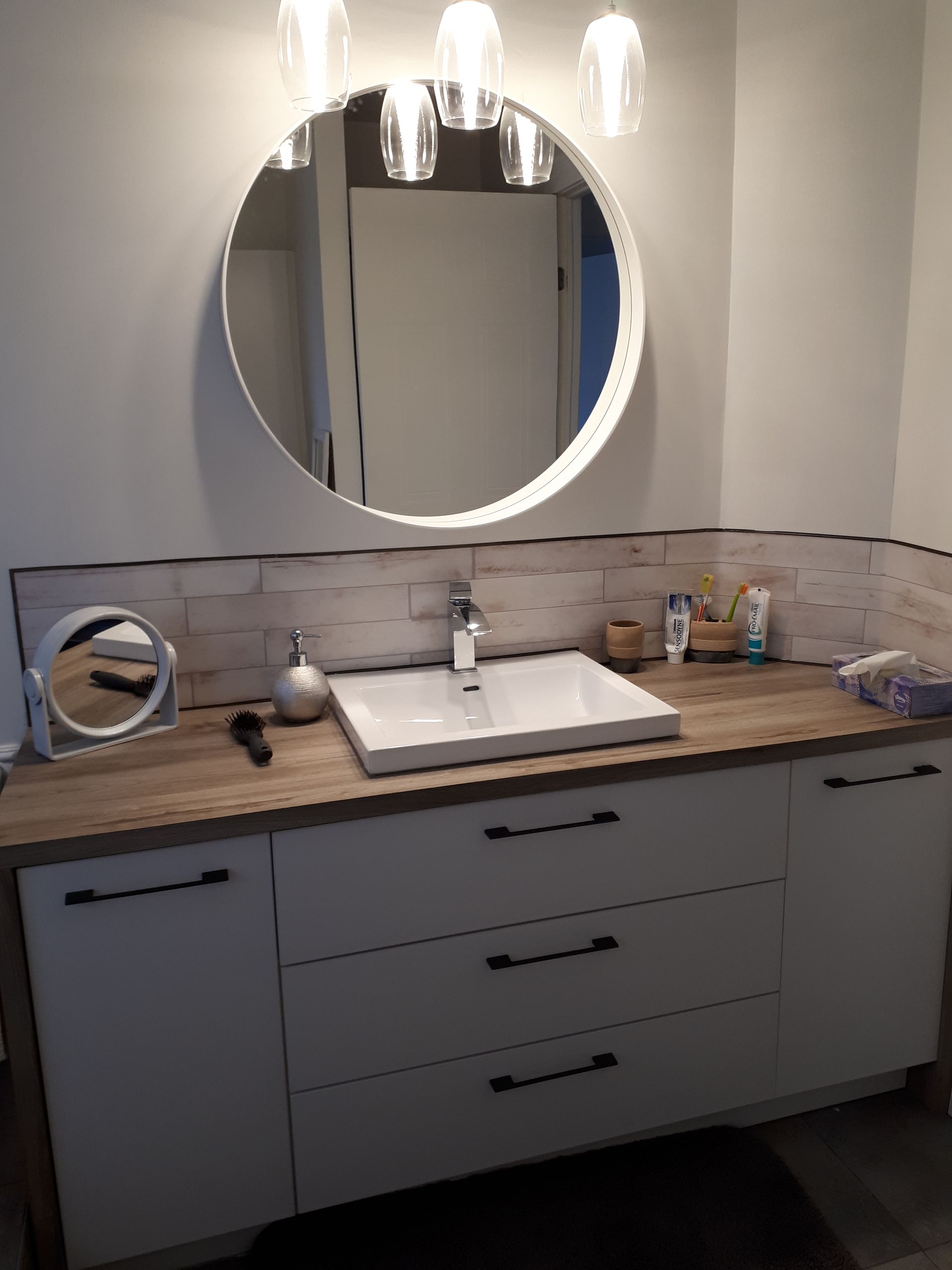 Une salle de bain avec lavabo et miroir rond