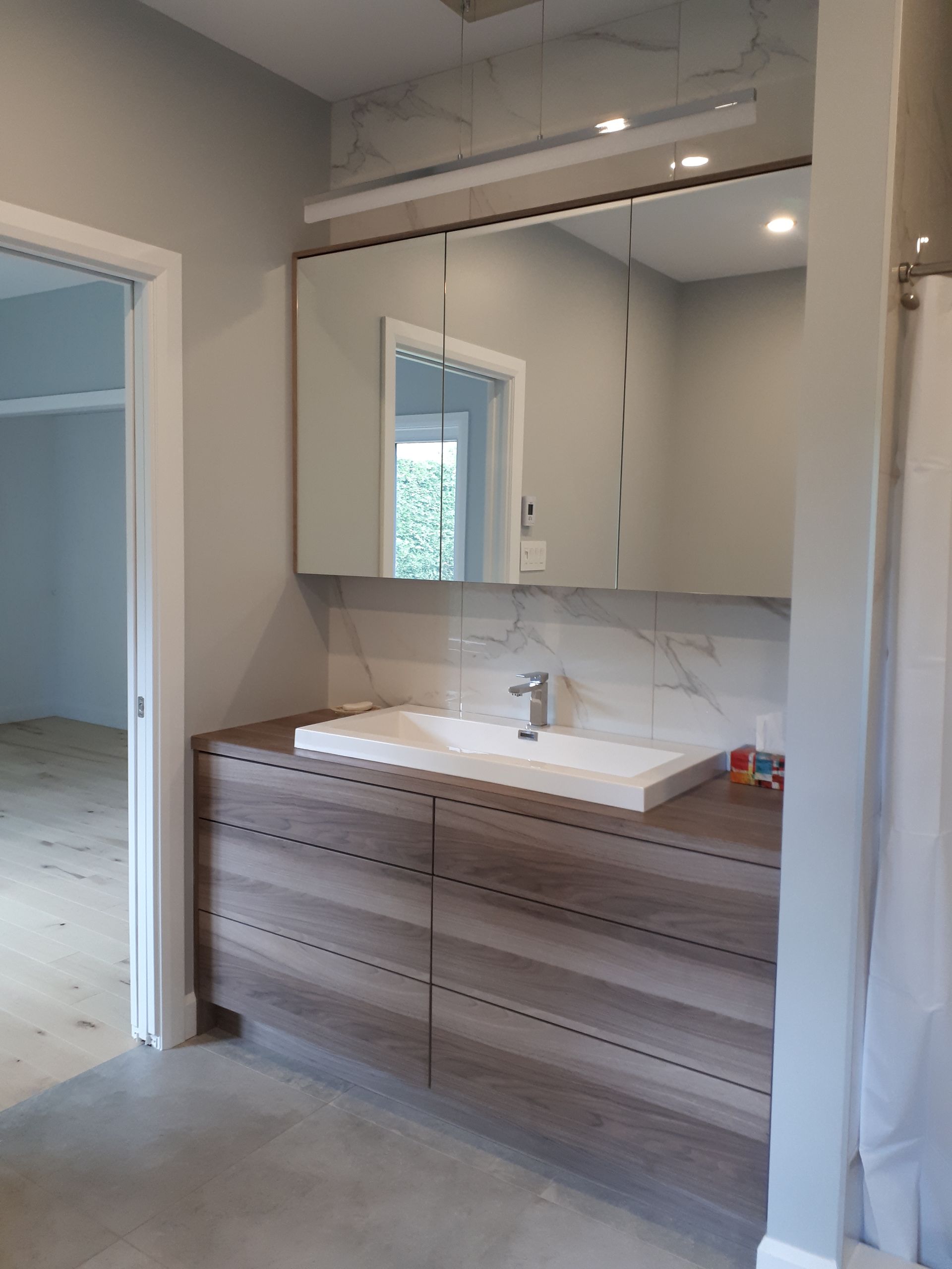 Une salle de bain avec lavabo , miroir et tiroirs.