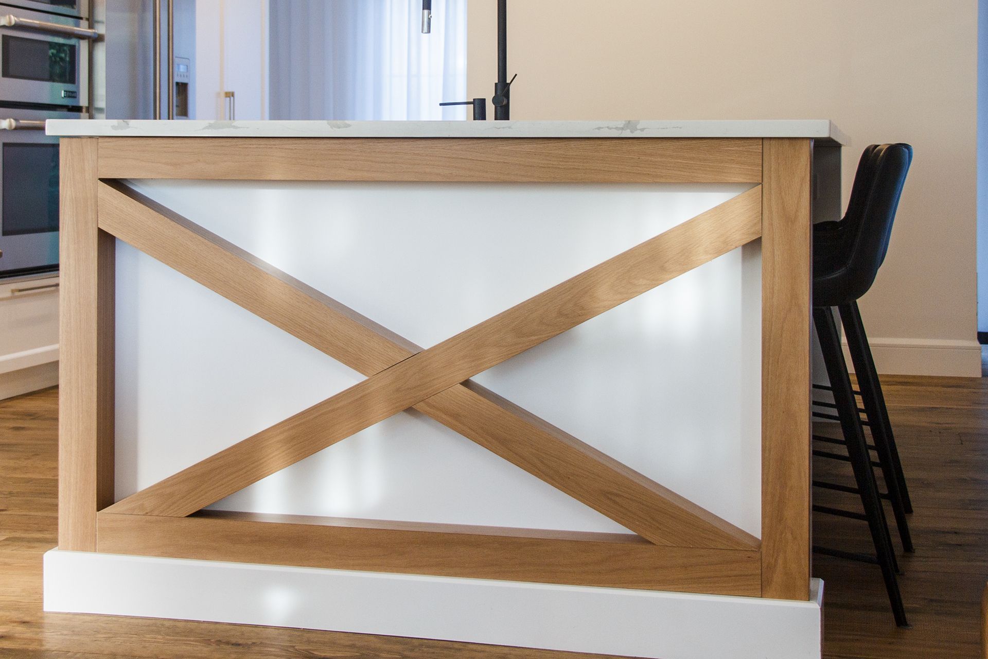Îlot de cuisine avec un plateau blanc, une structure en bois et des accents blancs, avec des tabourets de bar noirs.