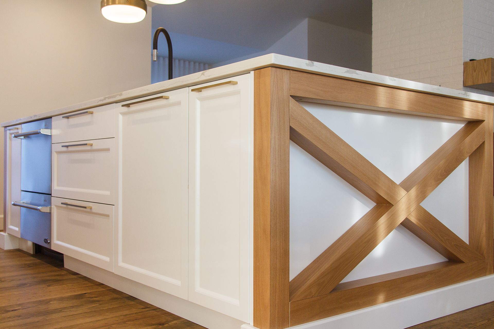 Îlot de cuisine avec armoires blanches, accents de bois clair et électroménagers intégrés.