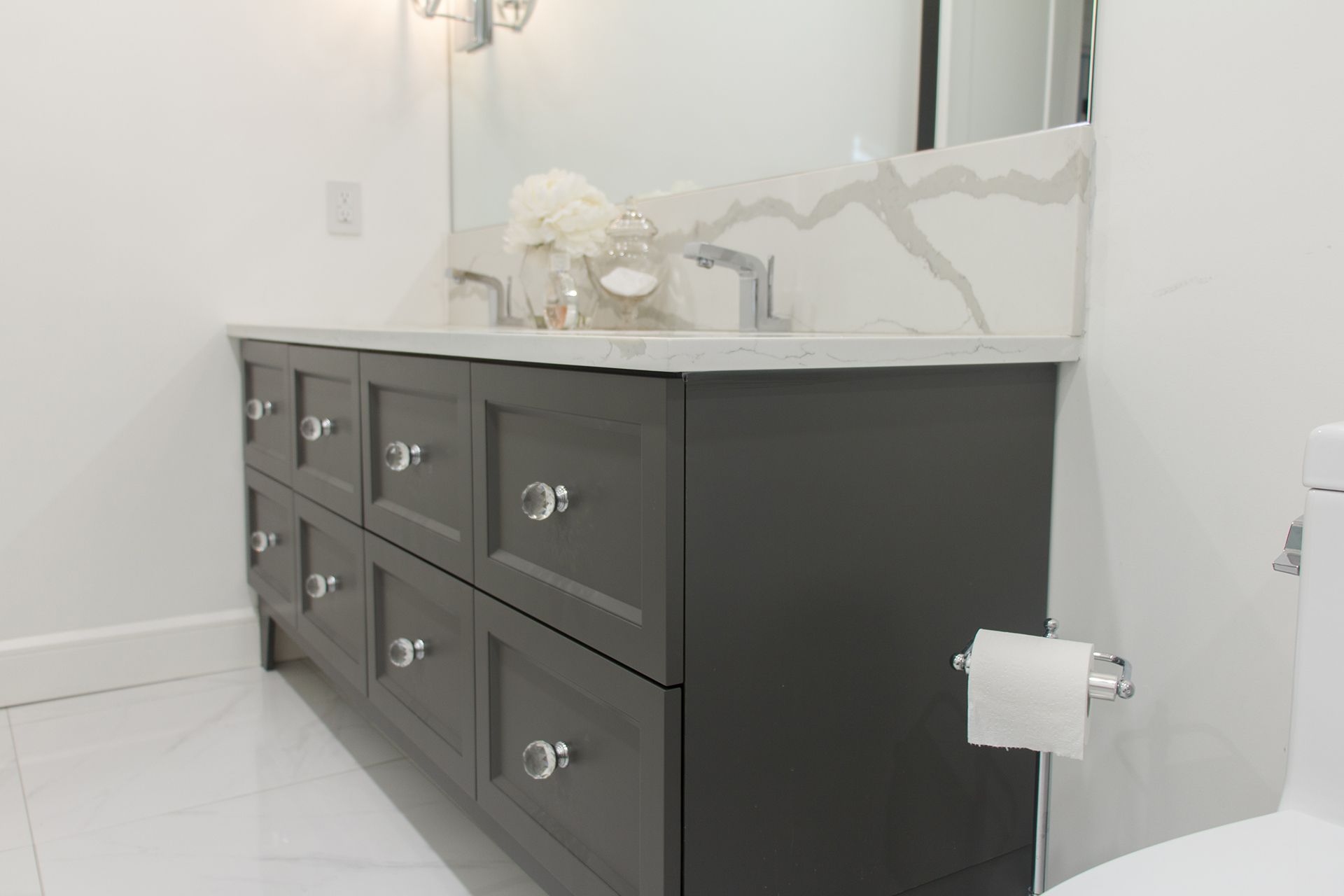 Meuble-lavabo gris avec poignées en cristal et comptoir en marbre.