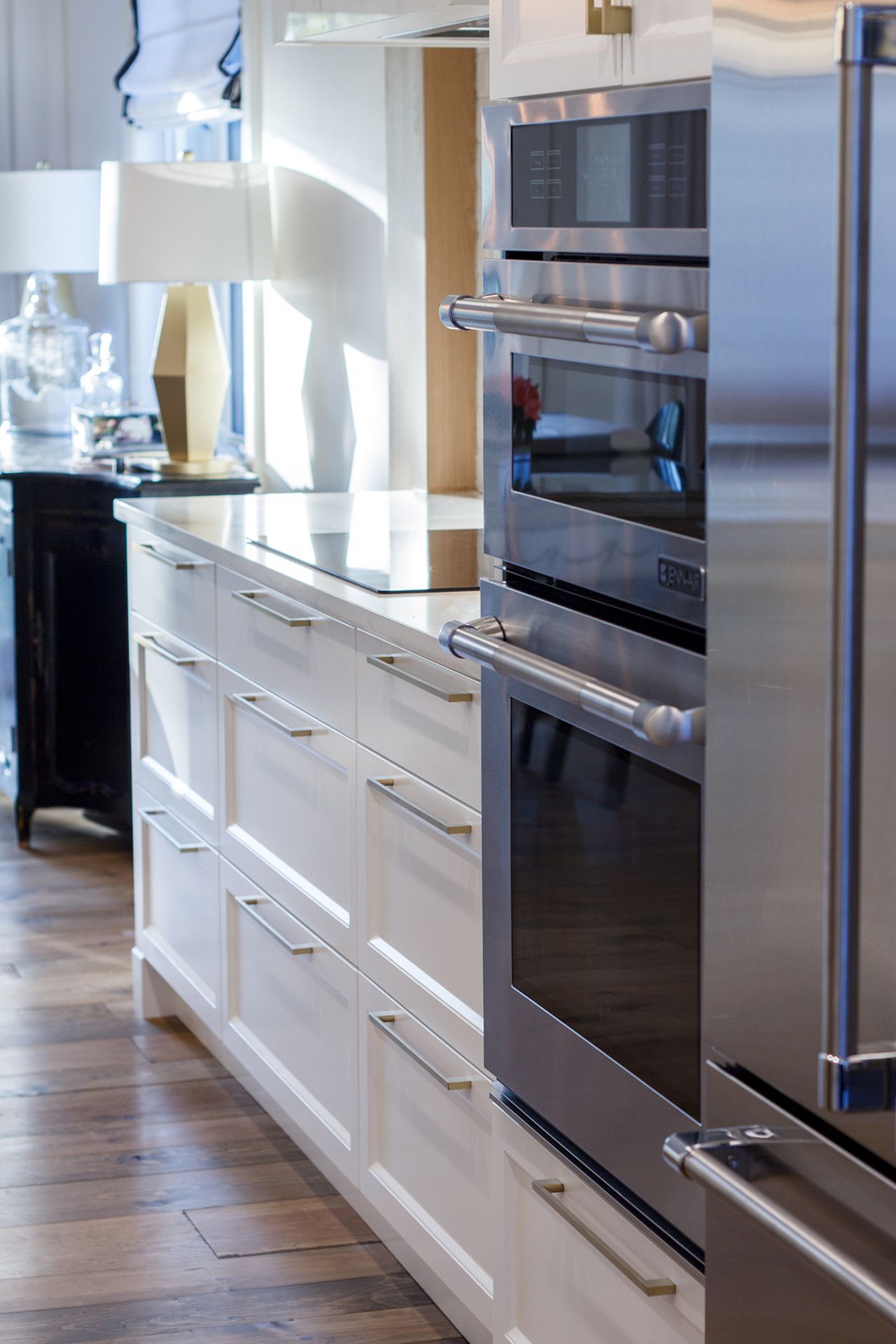 Cuisine équipée d'armoires blanches, four et réfrigérateur en acier inoxydable, planchers de bois franc.