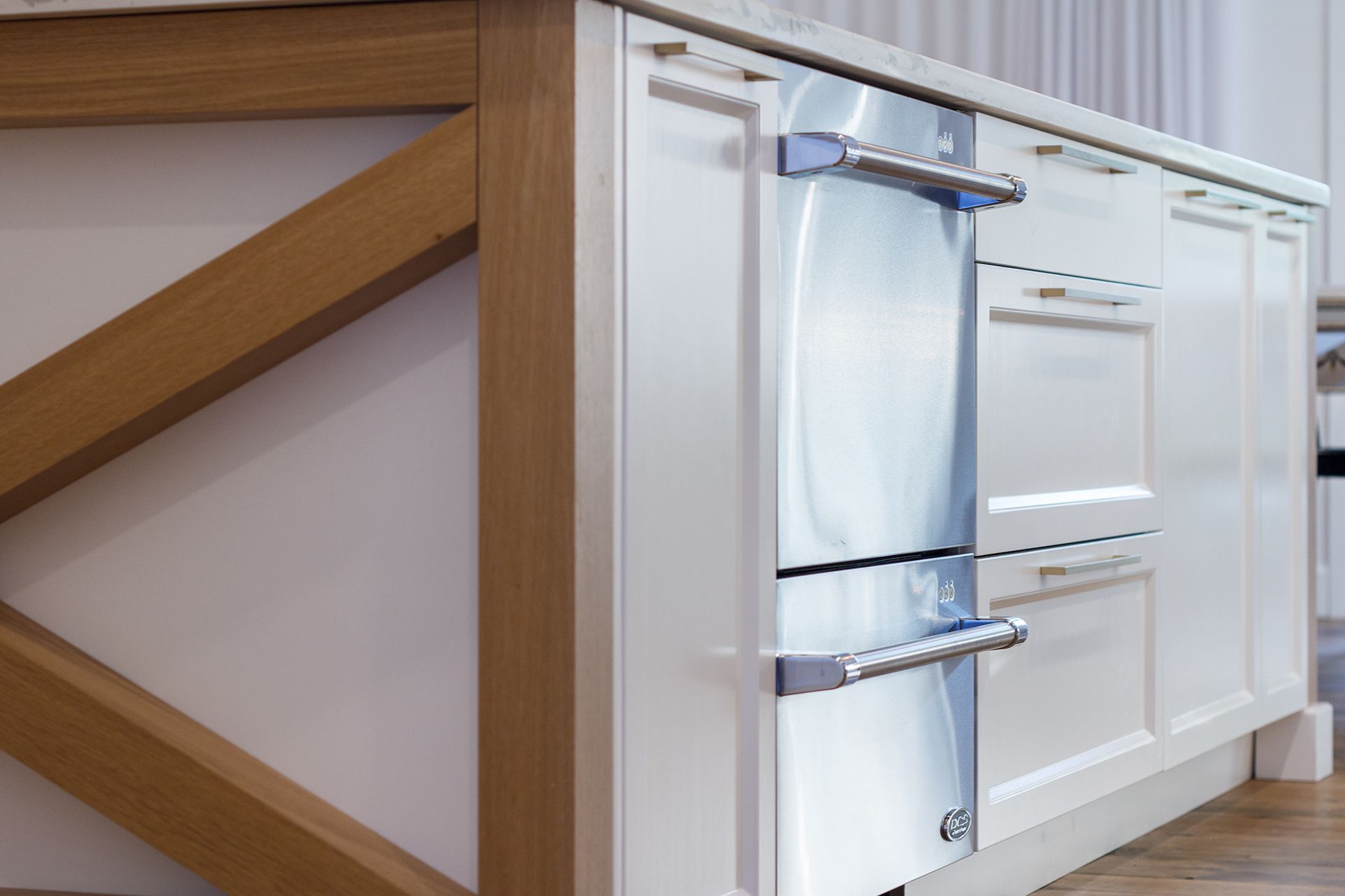 Îlot de cuisine blanc avec four en acier inoxydable et support en bois naturel.