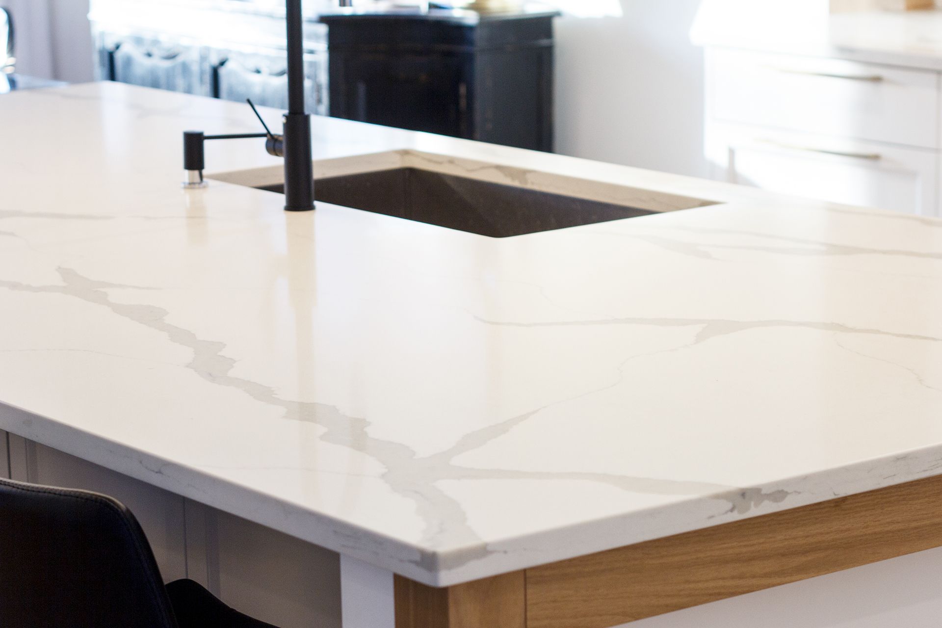 Comptoir en marbre blanc avec un évier et un robinet noir, dans une cuisine.