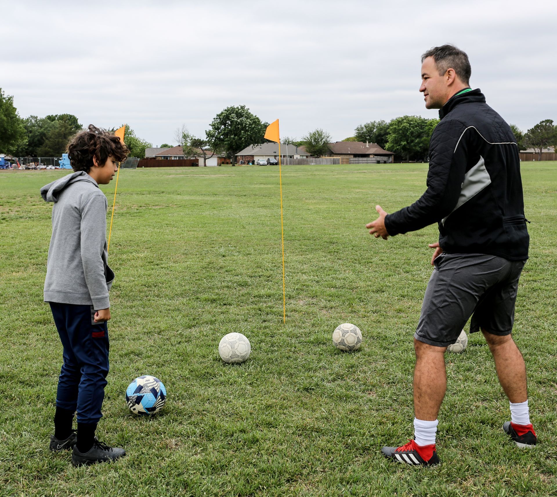 A coach is talking to two young boys on a soccer field.