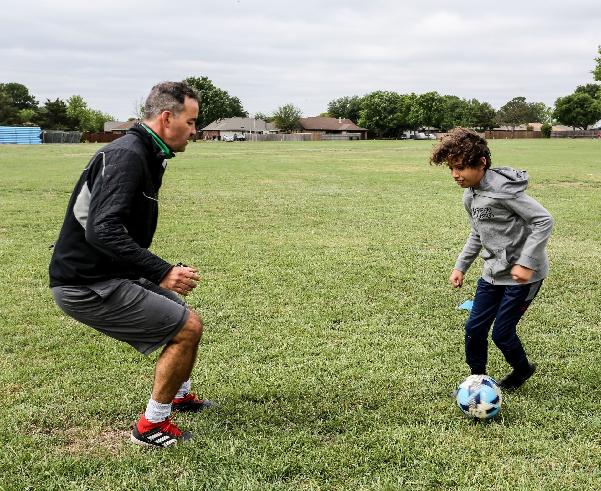 A soccer player is running on a ladder on a field.