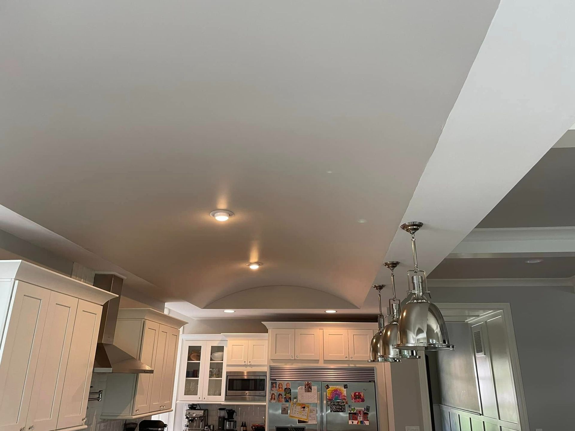 Kitchen with white cabinets, recessed lighting, and stainless steel pendant lights.