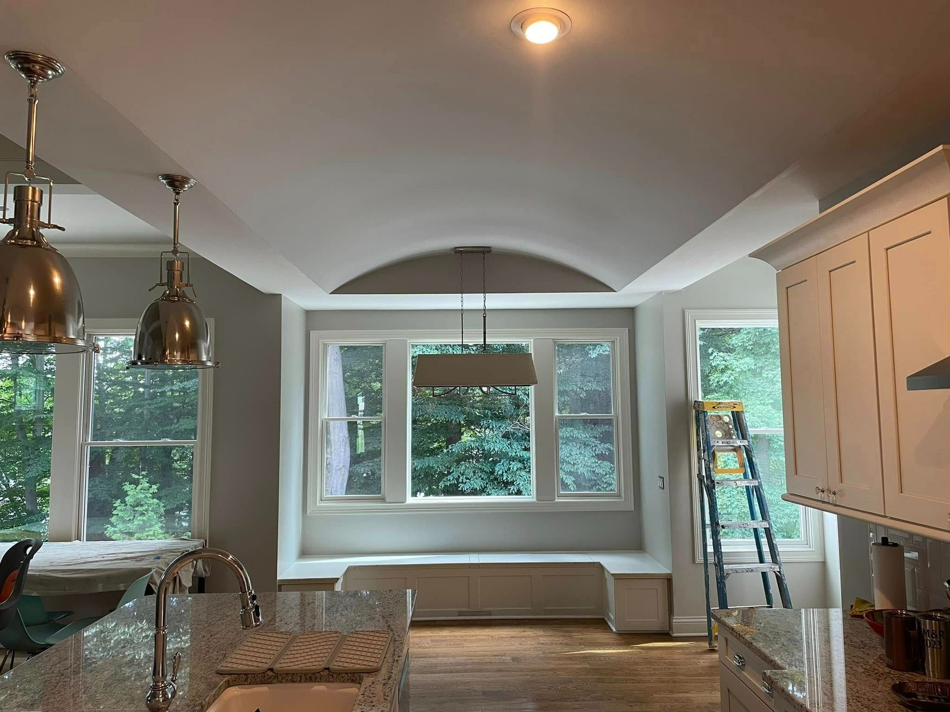 Kitchen with a curved ceiling detail, window seat, and pendant lights.