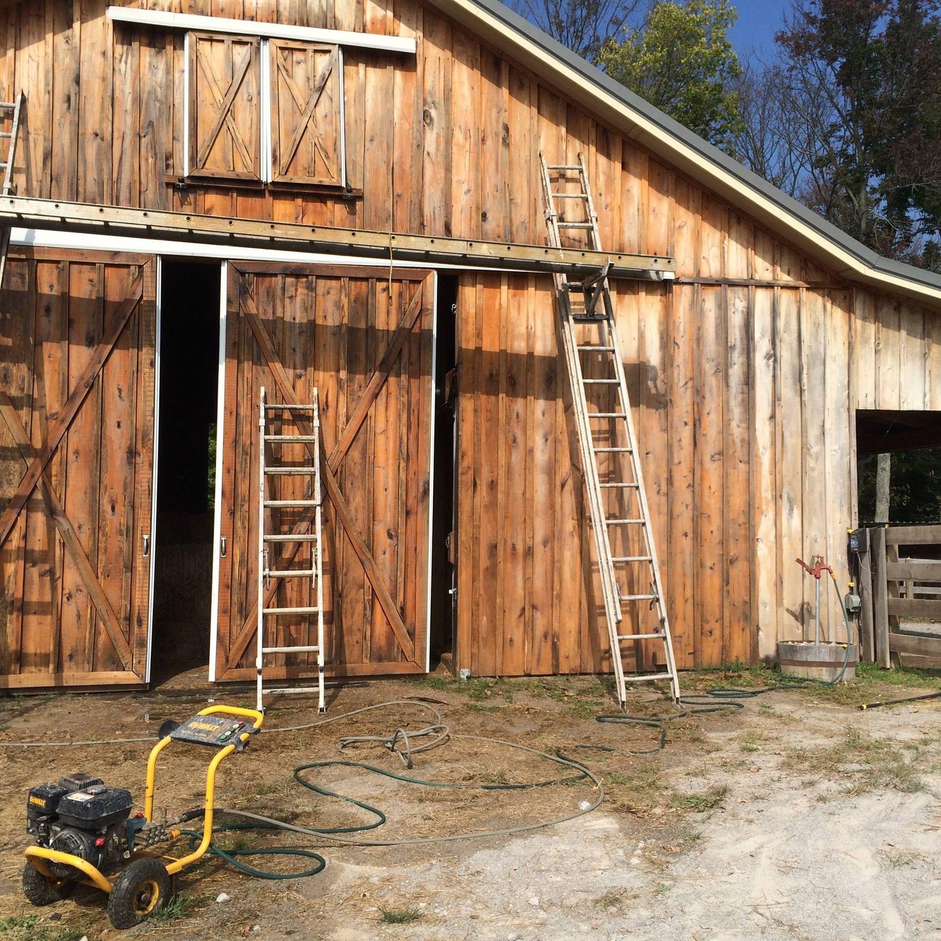 Barn with open sliding doors, ladders, and a yellow pressure washer.