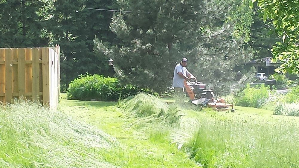 A man is mowing his lawn with a lawn mower
