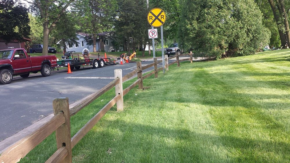 A railroad crossing sign is next to a wooden fence
