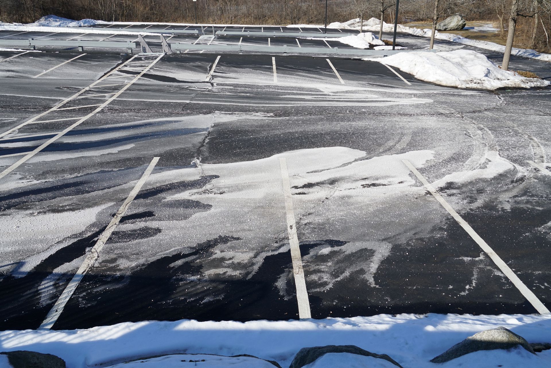 Snowy parking lot with white lines, partially covered in snow and ice.