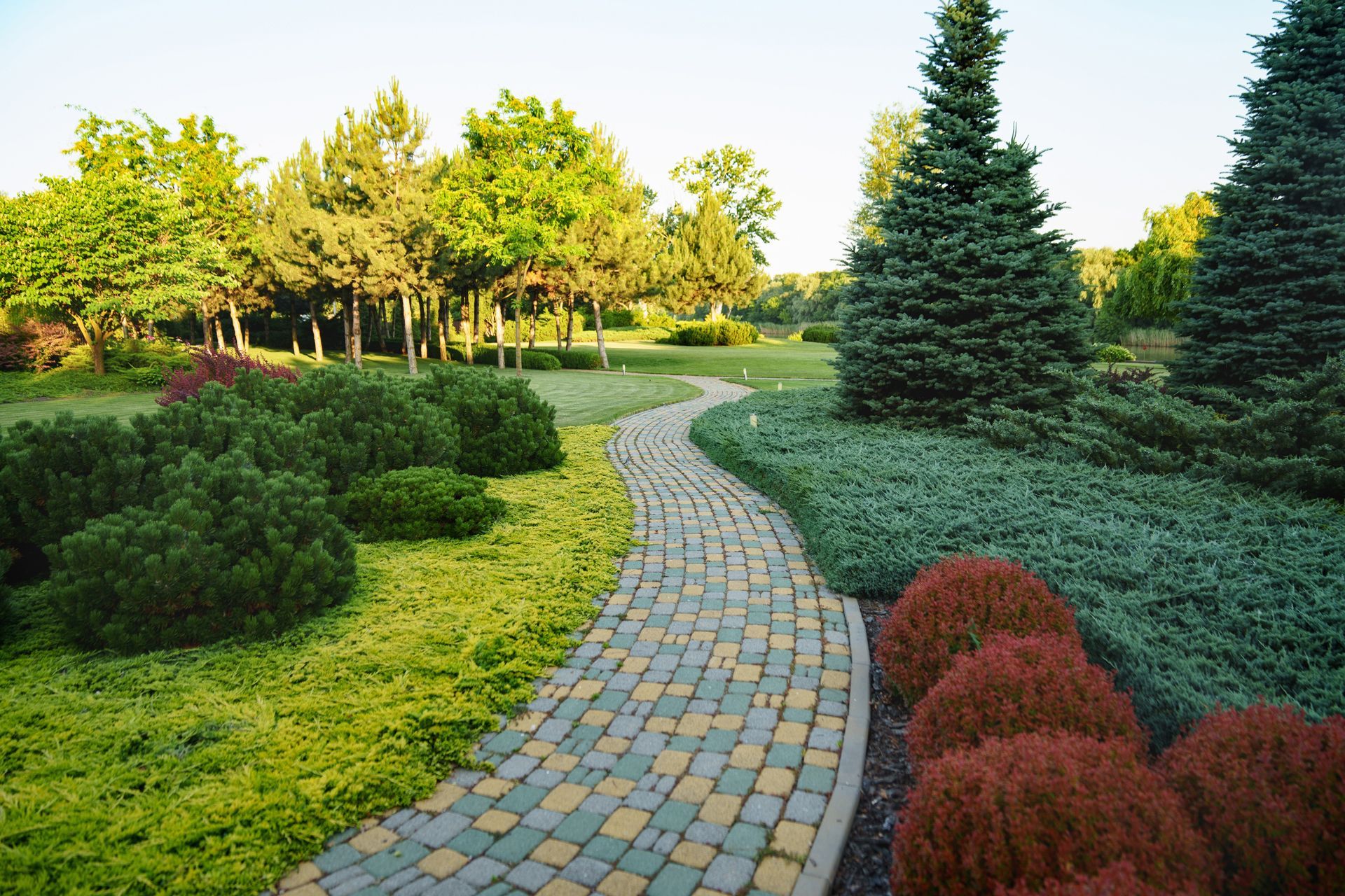 A brick walkway in a park surrounded by trees and bushes
