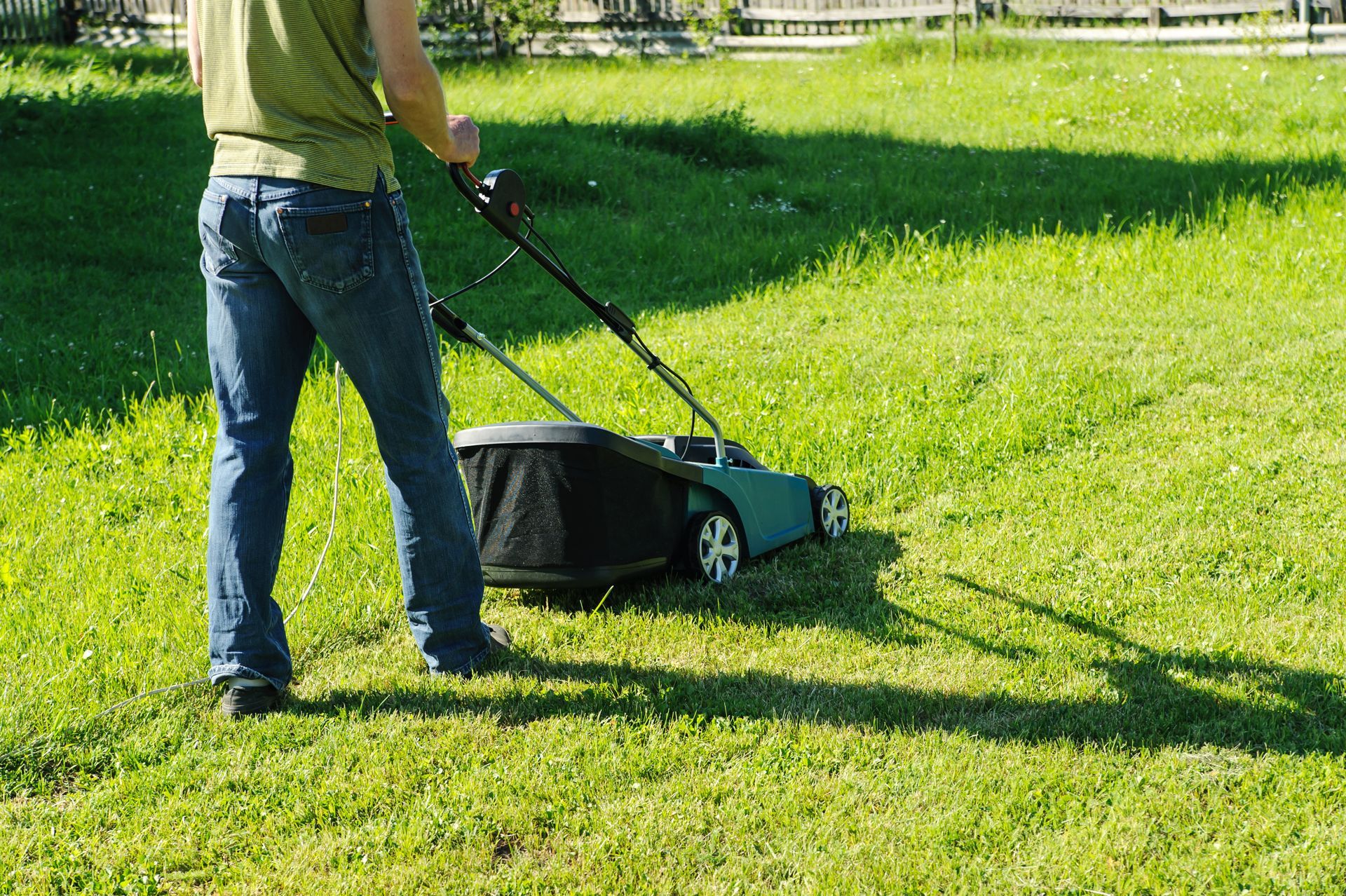 A man is mowing a lush green lawn with a lawn mower