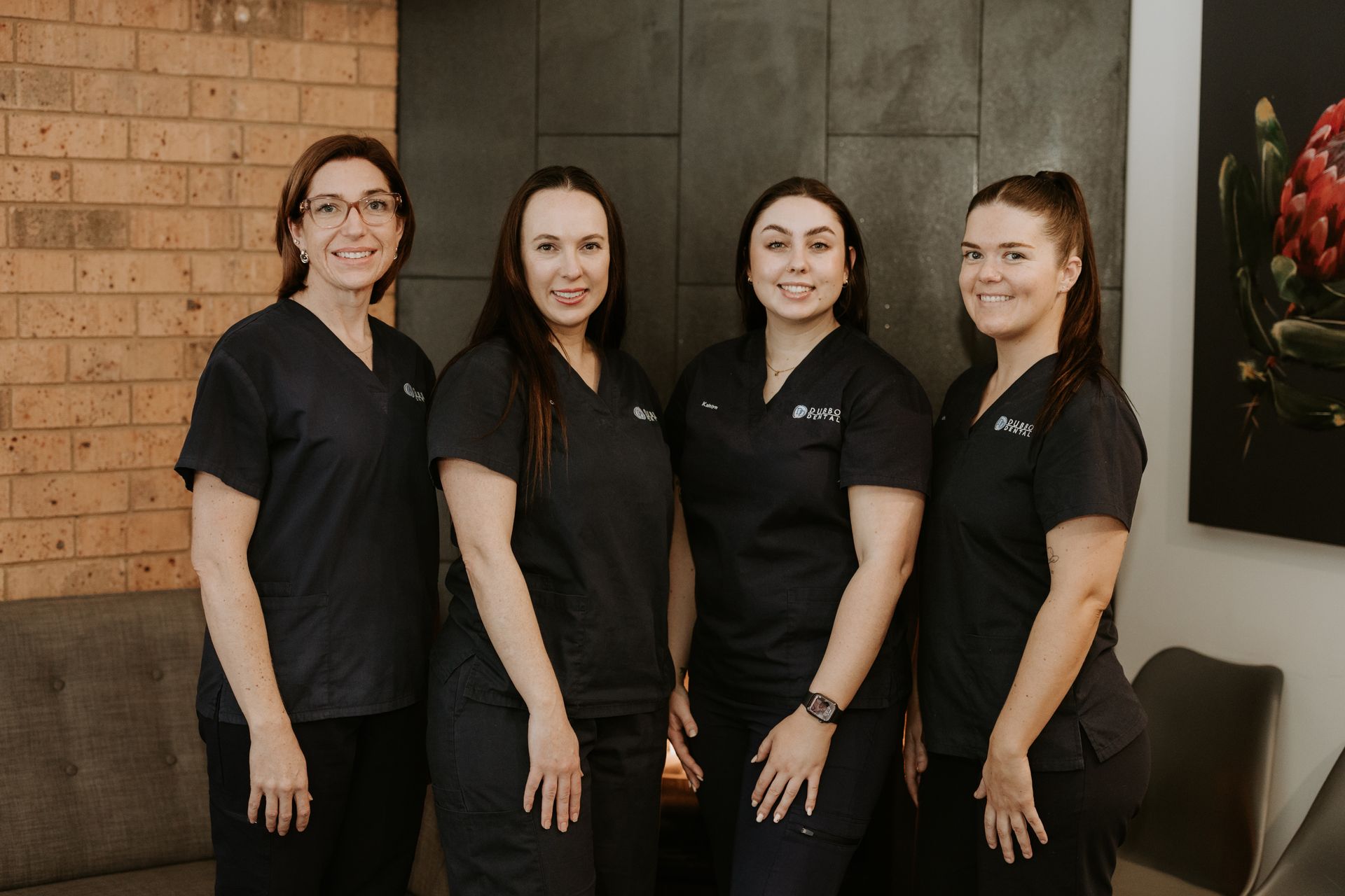 Four Women Smiling, Posing for a Photo in a Modern Office Setting — Dubbo Dental in Dubbo, NSW