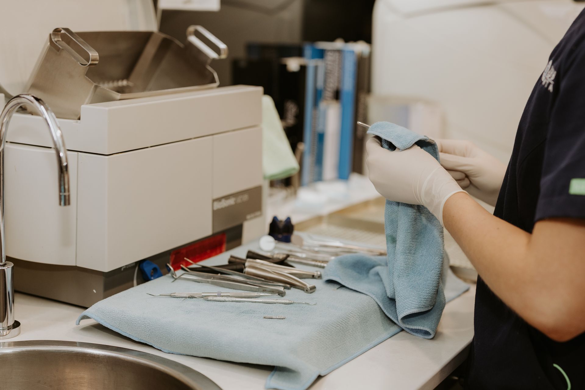 Person in Gloves Wipes Dental Tools at a Sink, Near Sterilization Equipment — Dubbo Dental in Dubbo, NSW