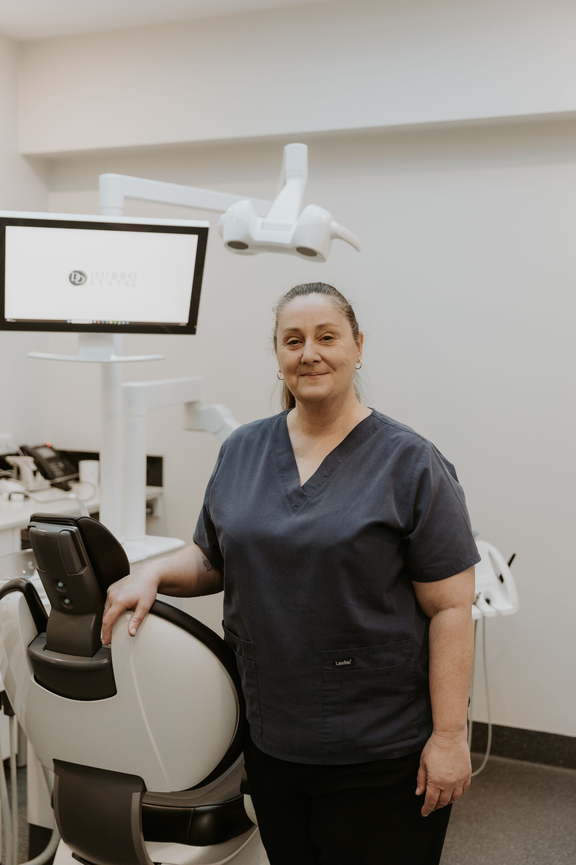 Woman in Blue Scrubs Stands by Dental Chair in a Dentist's Office — Dubbo Dental in Dubbo, NSW
