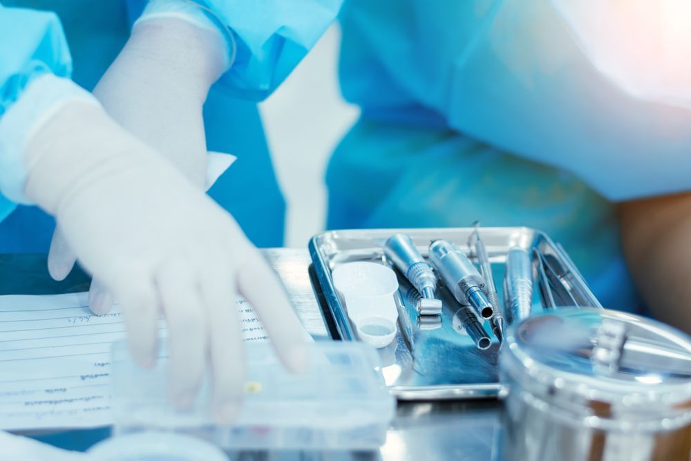 A Close Up of a Surgeon's Hands Reaching for a Tray of Surgical Instruments — Dubbo Dental in Dubbo, NSW