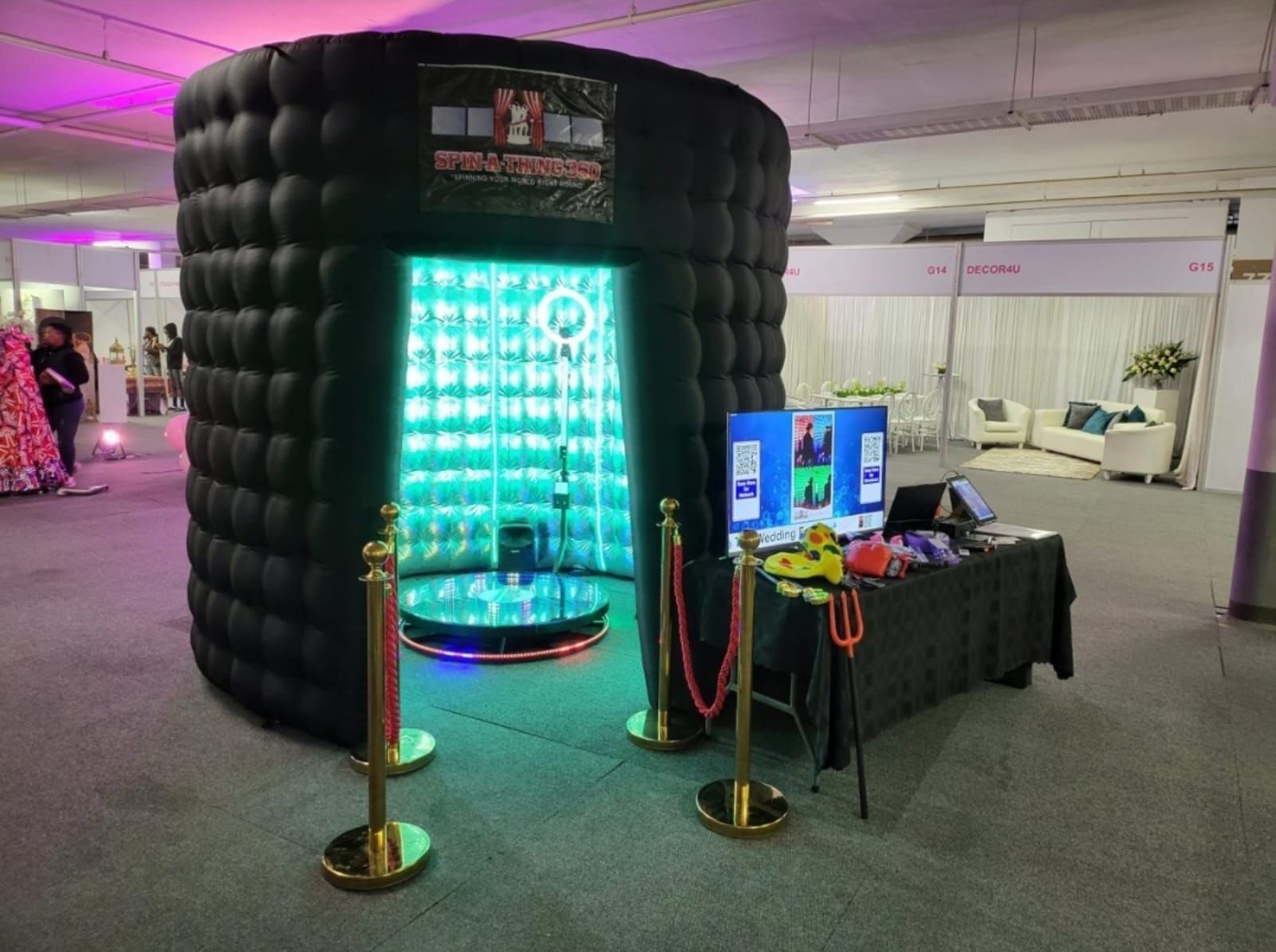 A black inflatable photo booth is sitting in a large room.