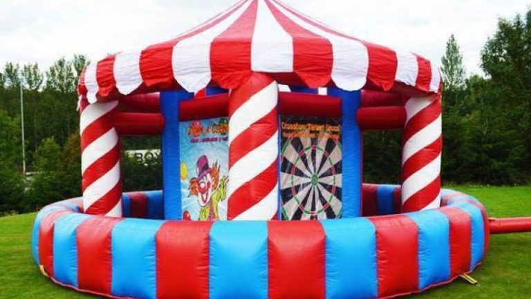A red and blue inflatable merry go round with a dart board inside of it.