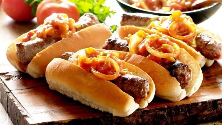 A bunch of hot dogs sitting on top of a wooden cutting board.