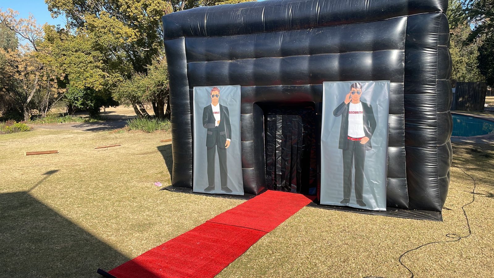 There is a red carpet leading to a black inflatable building.