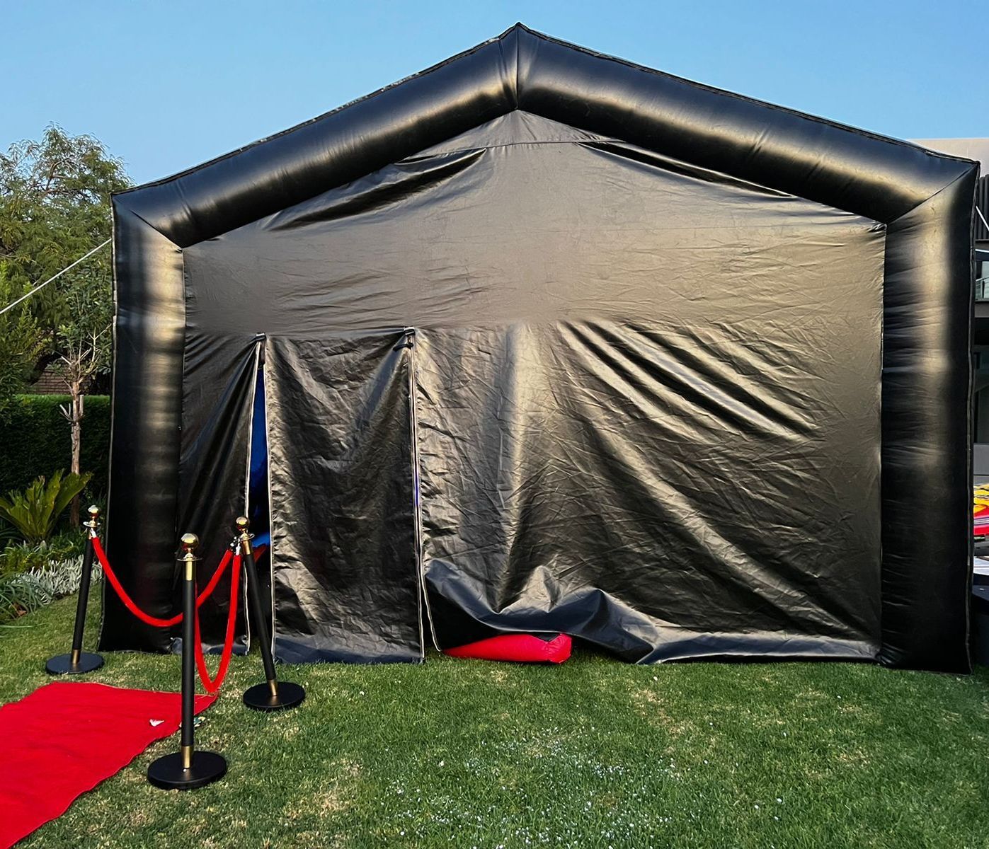 A black inflatable tent with a red carpet in front of it