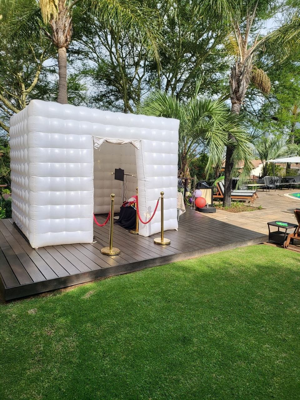 A white inflatable tent is sitting on top of a wooden deck in a park.