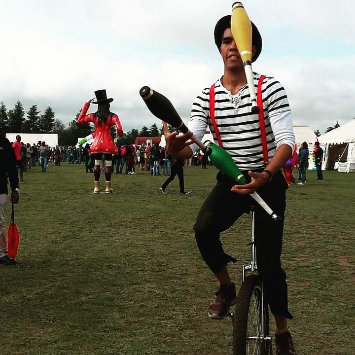 A man riding a bike with a juggling stick in his hand