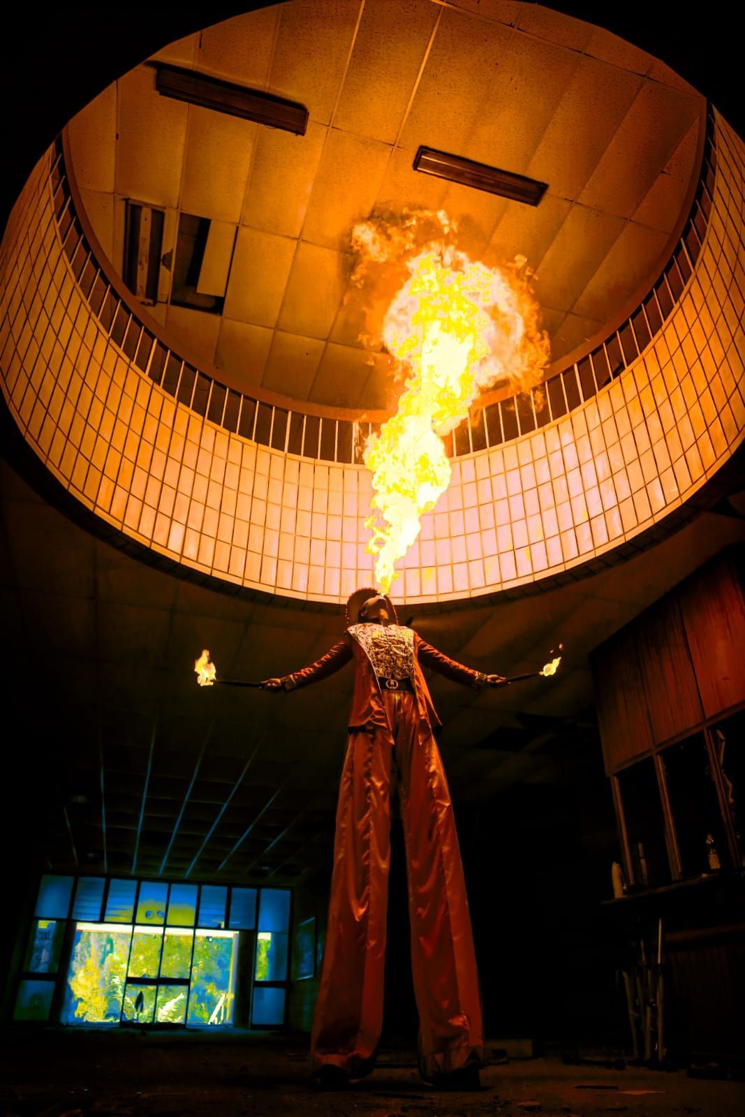 A person on stilts with flames coming out of their mouth