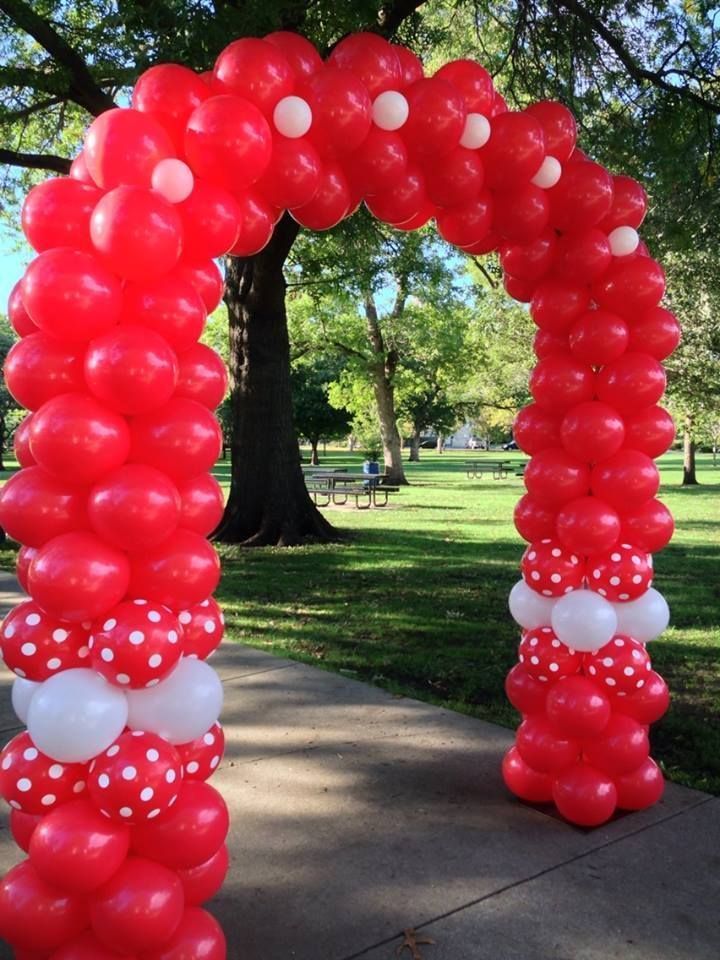 A red and white balloon arch in a park