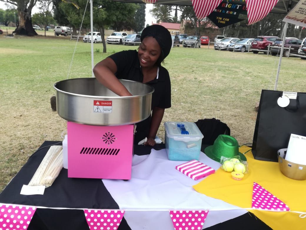 A woman is making cotton candy in a pink machine