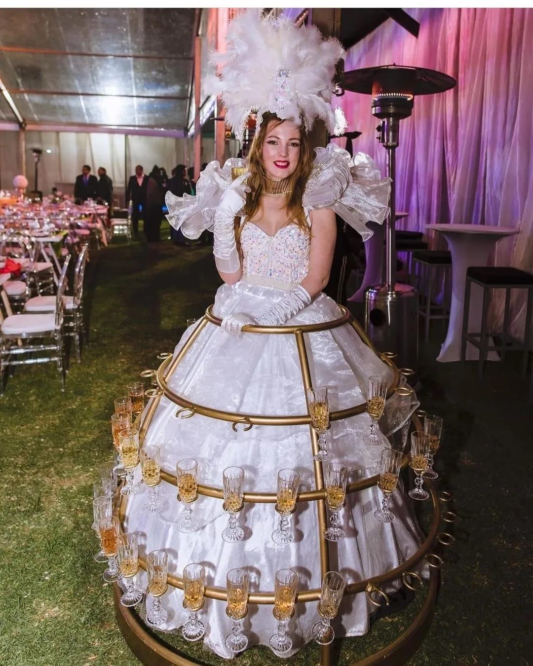 A woman in a white dress is standing in a display of wine glasses