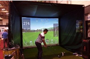A man is playing a video game of golf in a simulator.