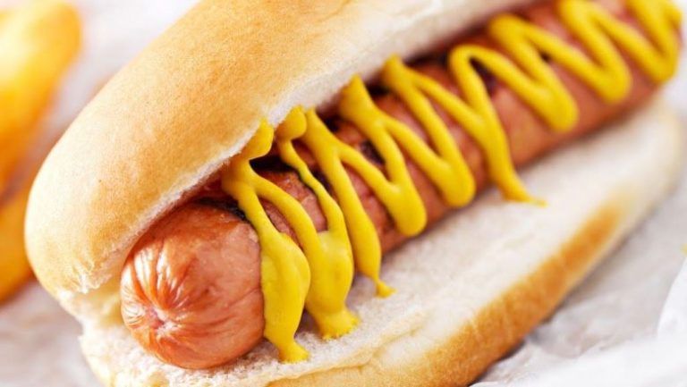 A hot dog on a bun with mustard on it