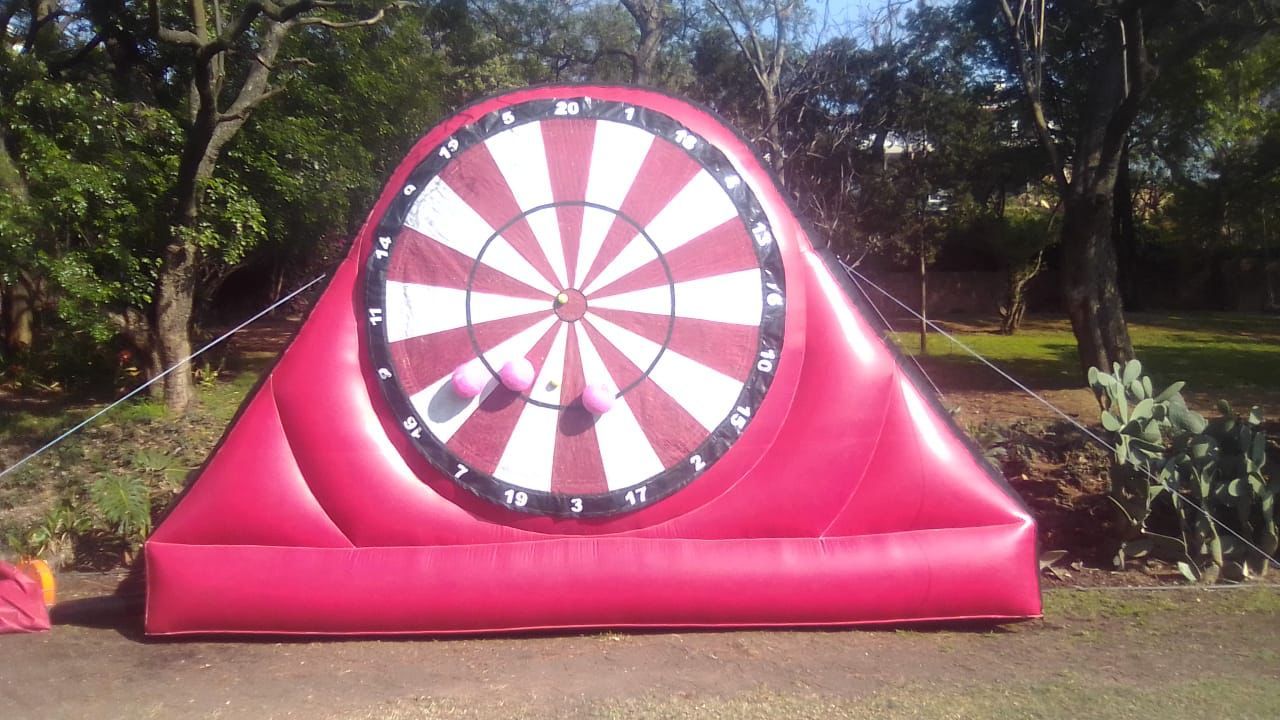 A large inflatable dart board is sitting on the ground in a park.