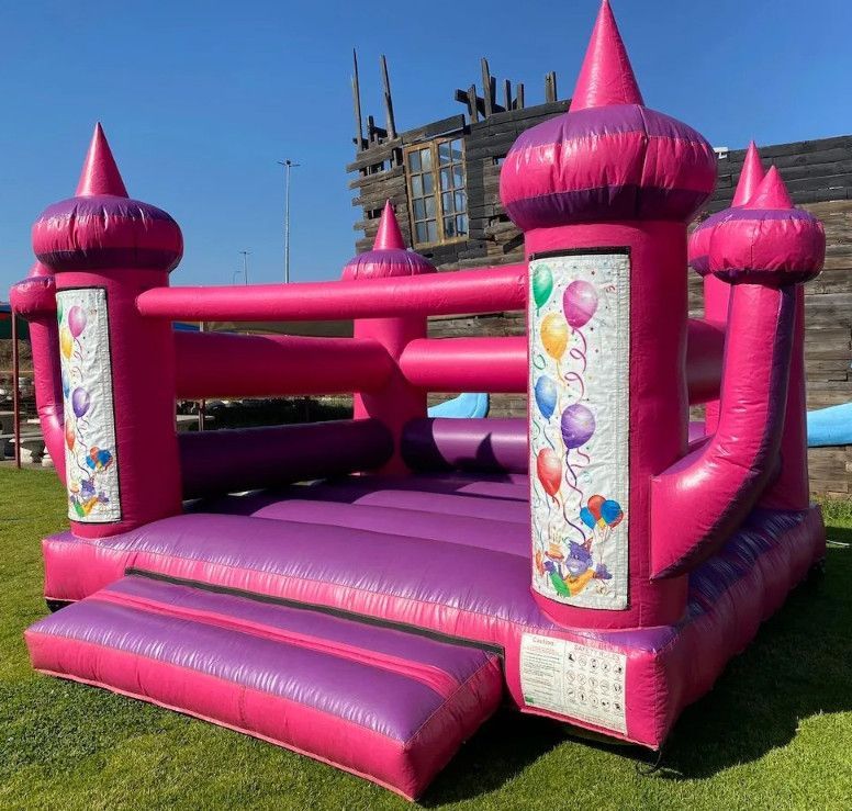 A pink and purple bouncy castle with balloons on it