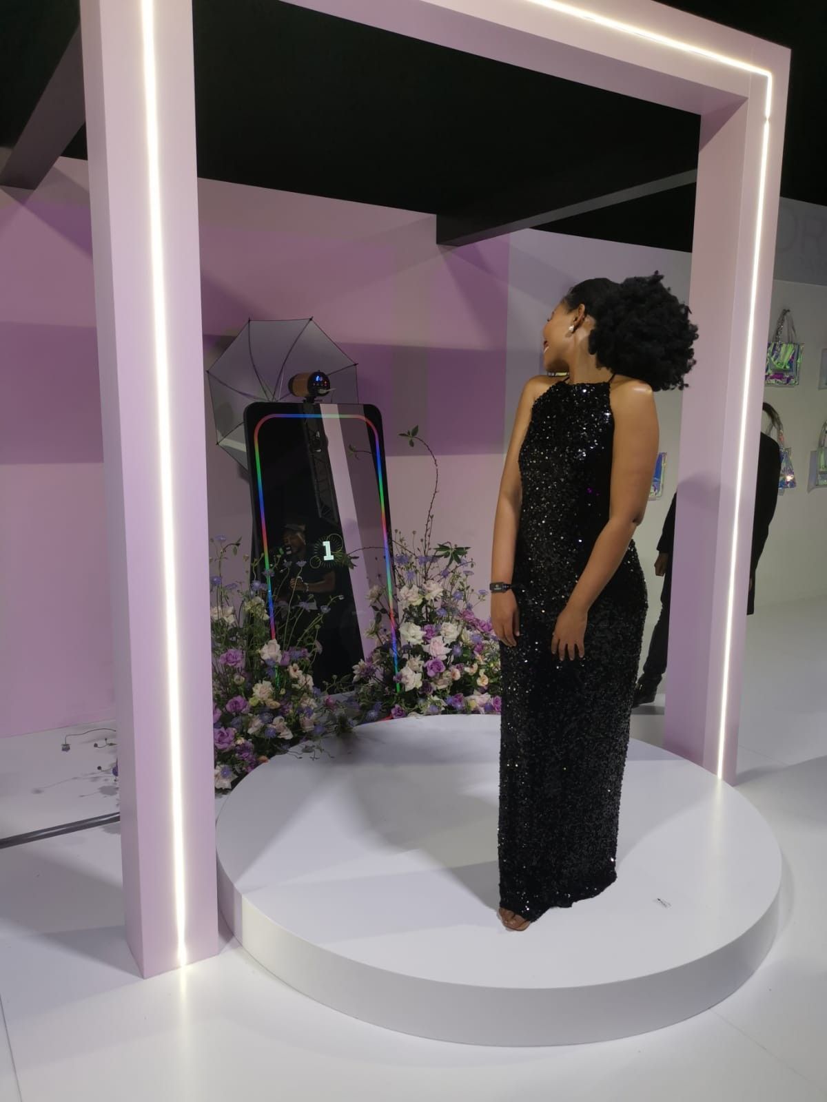 A woman in a black dress is standing in front of a mirror