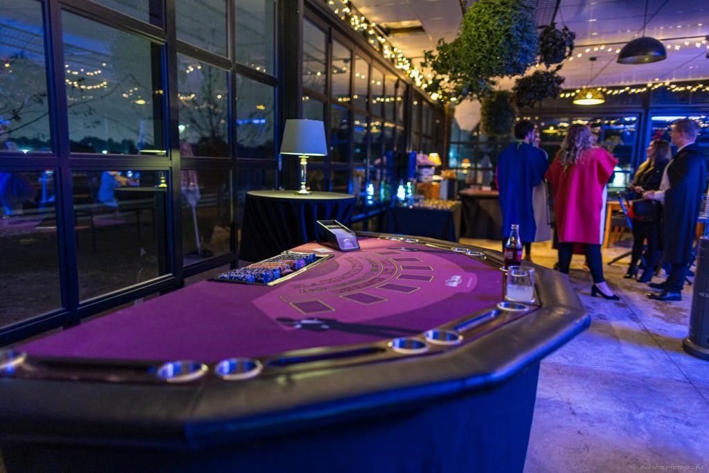 A group of people are standing around a roulette table in a room.
