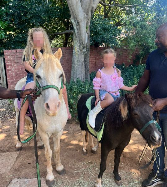 Two children are riding on the backs of two horses.