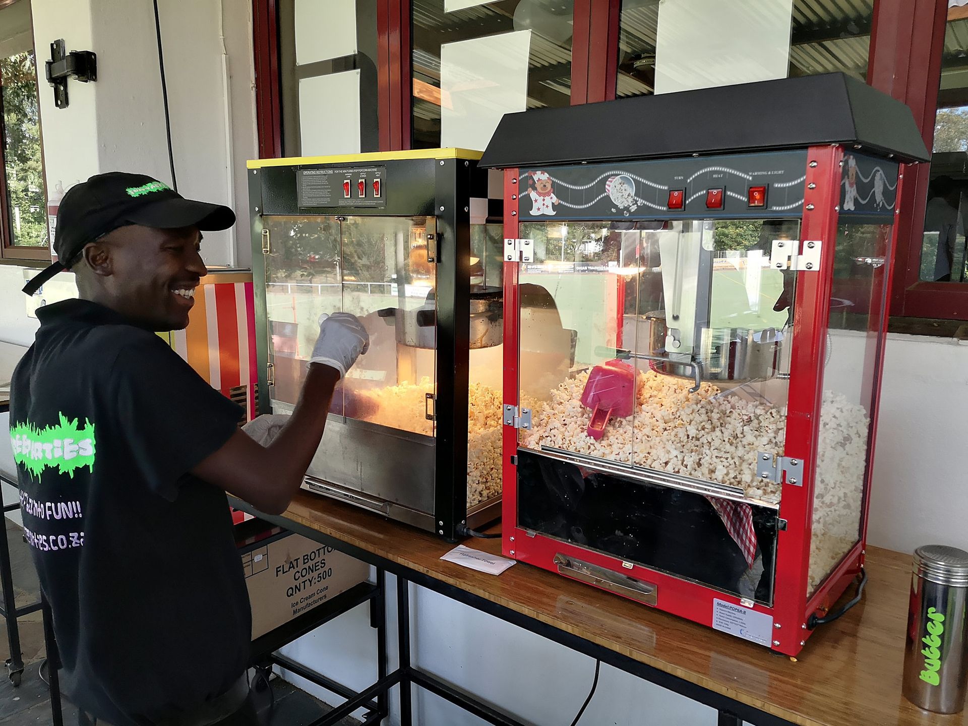 A man is standing in front of a popcorn machine.