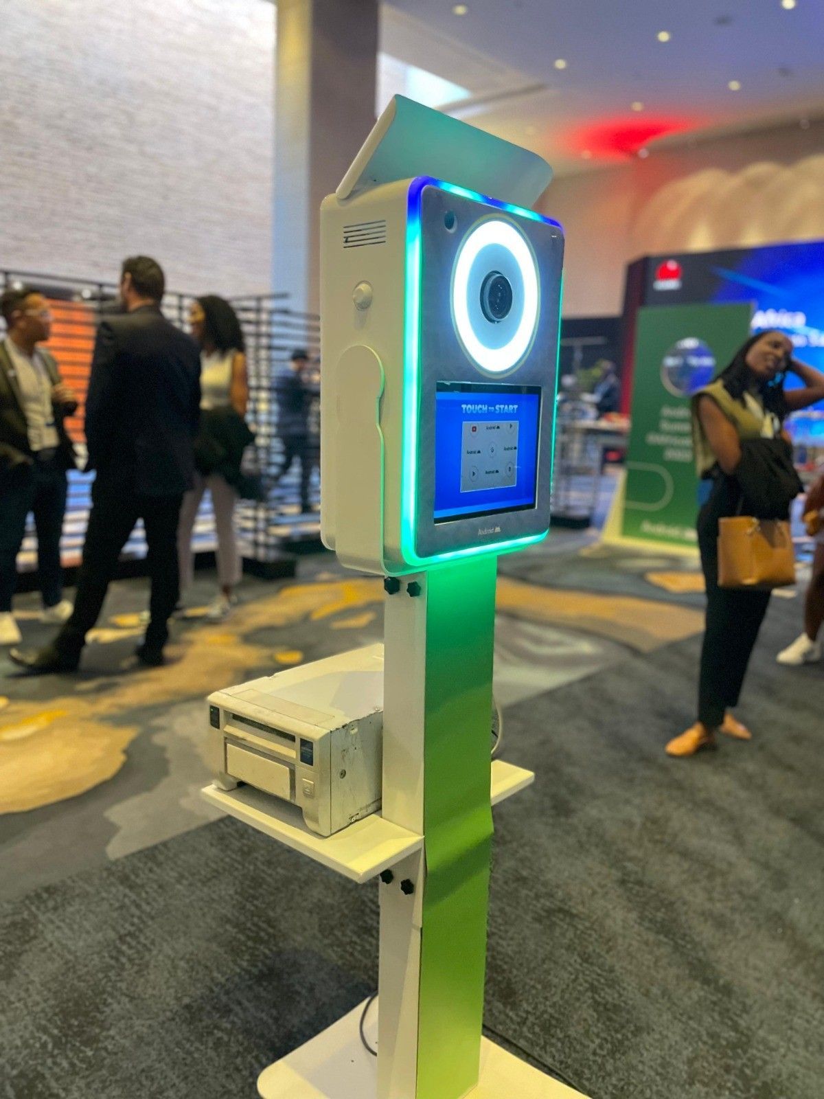 A photo booth is sitting in a room with people standing around it.