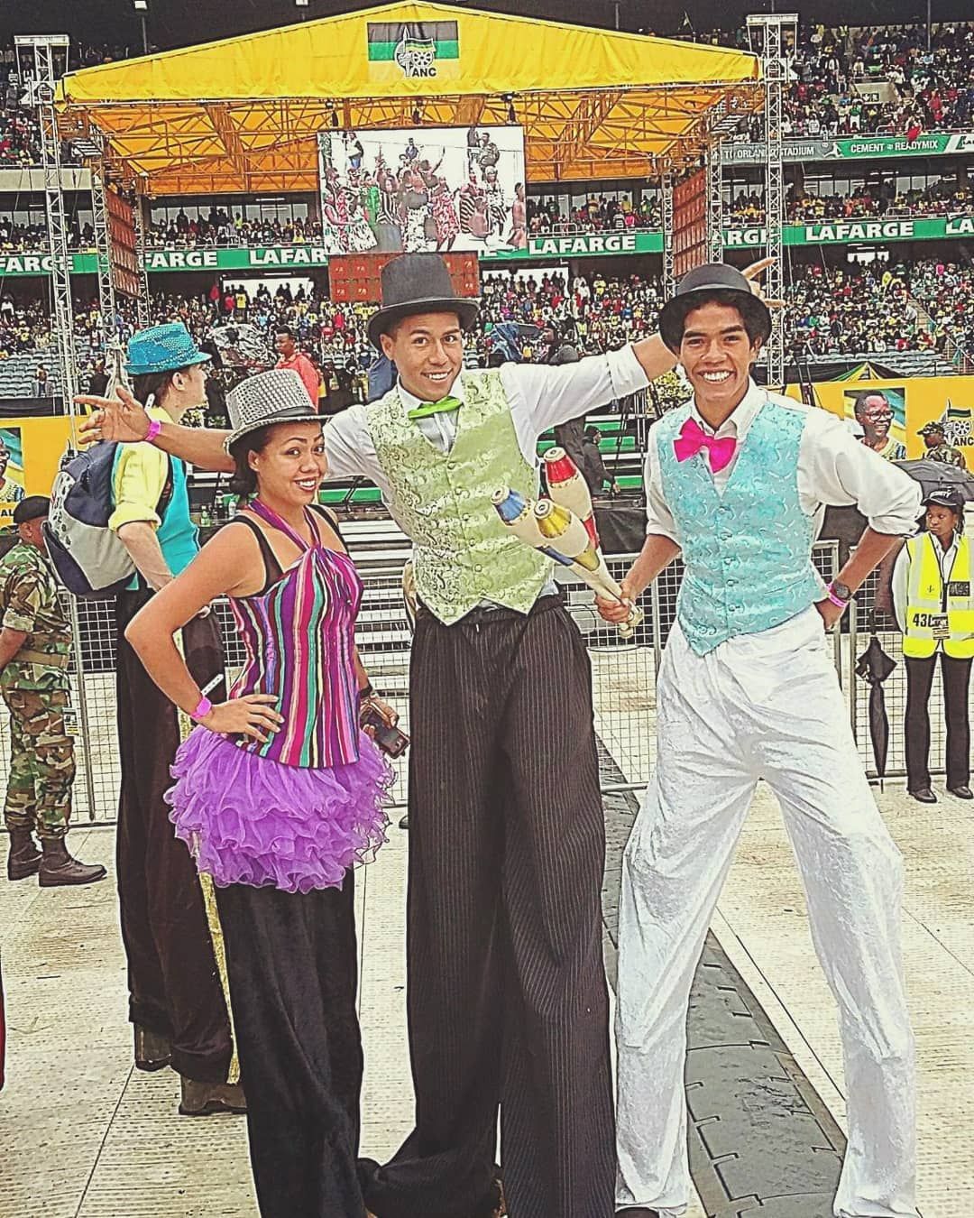 A group of people standing on stilts in front of a crowd