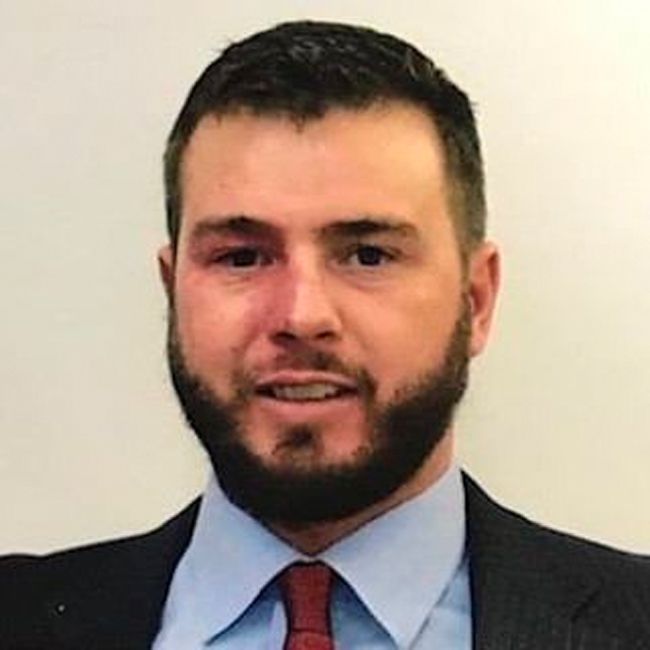 A man with a beard is wearing a suit and tie.