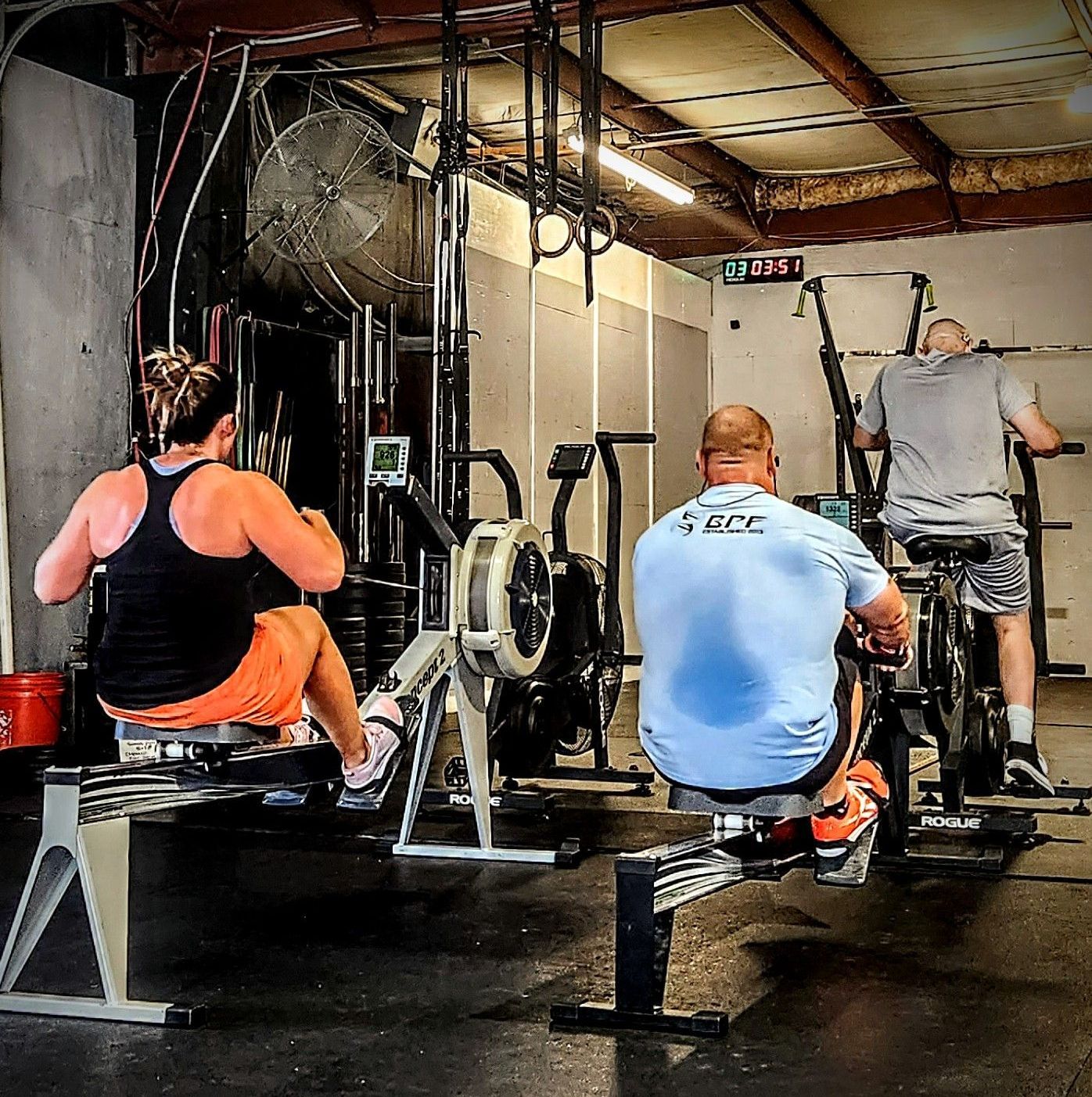 A man wearing a shirt that says 4 ece is riding a bike in a gym