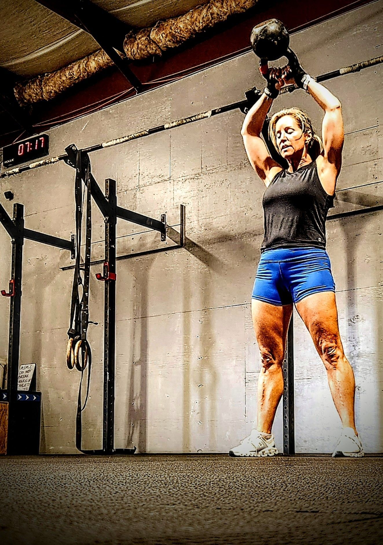 A woman is lifting a kettlebell in a gym.
