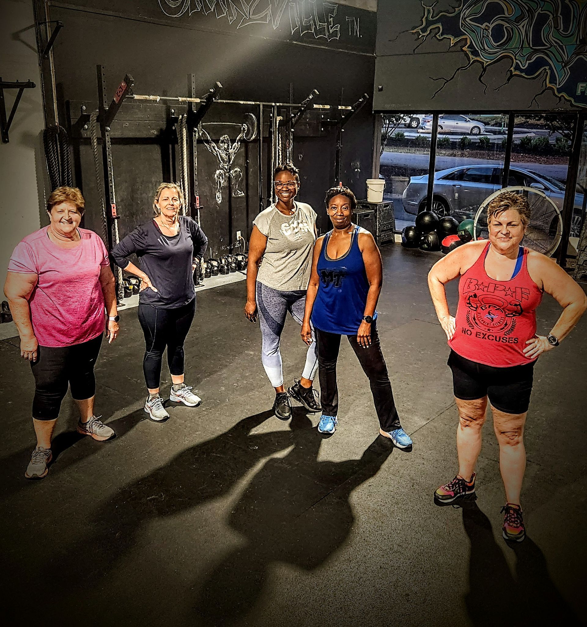 A group of women are posing for a picture in a gym