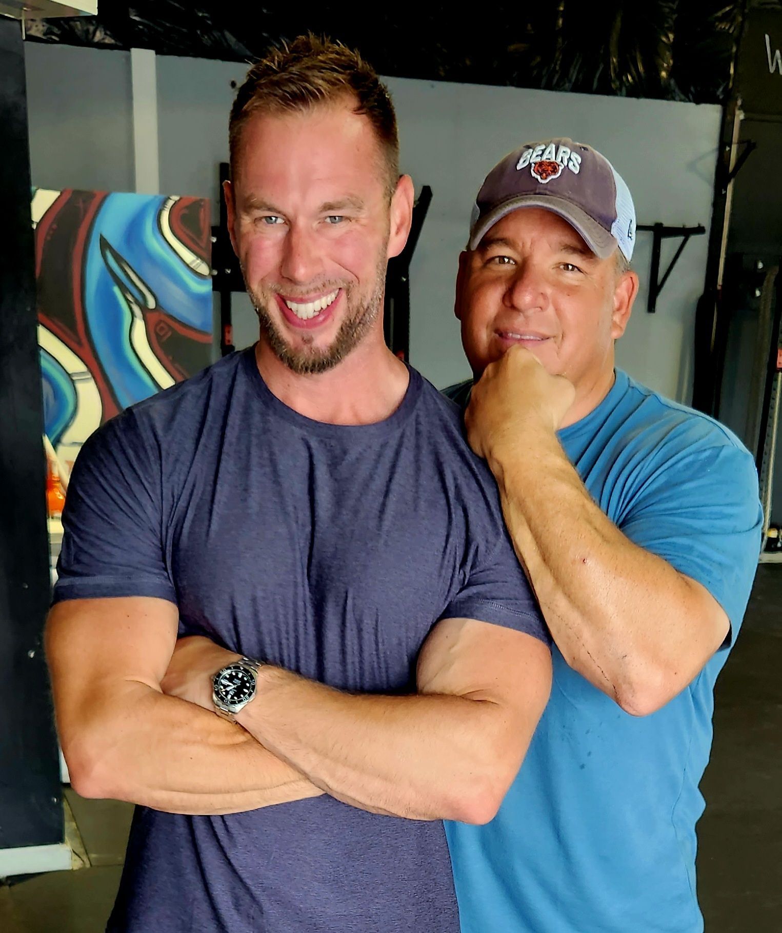 Two men are posing for a picture with one wearing a bears hat