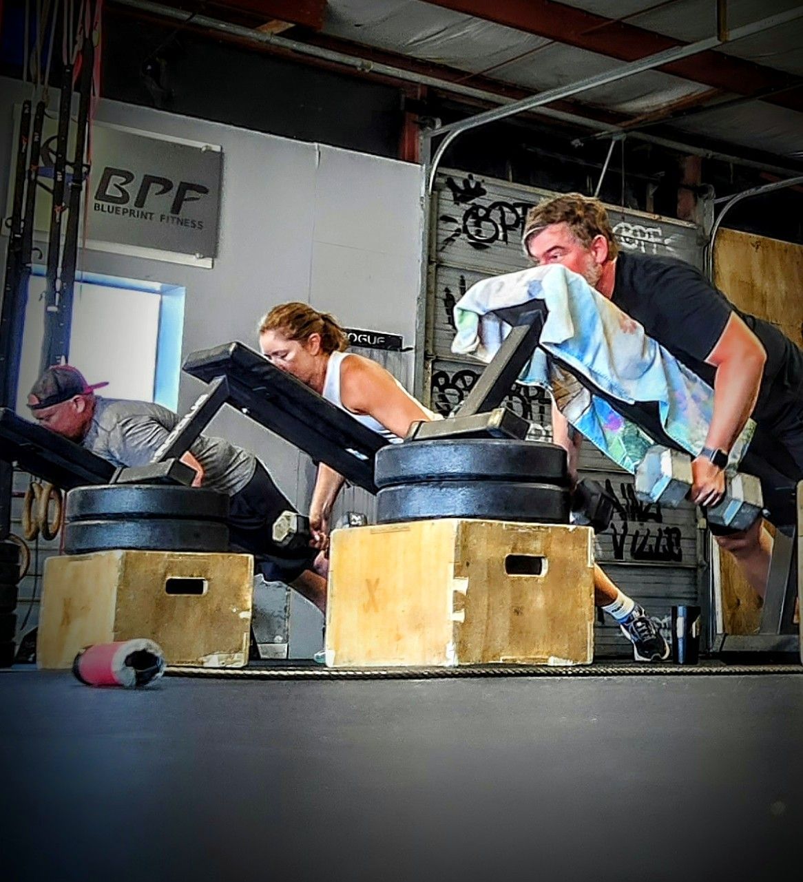 A man and a woman are lifting dumbbells in a gym.