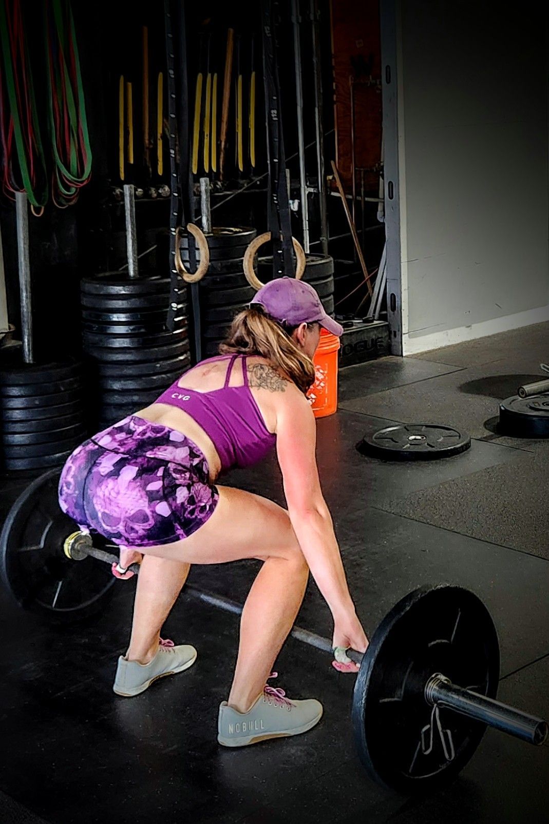A woman is lifting a barbell in a gym.